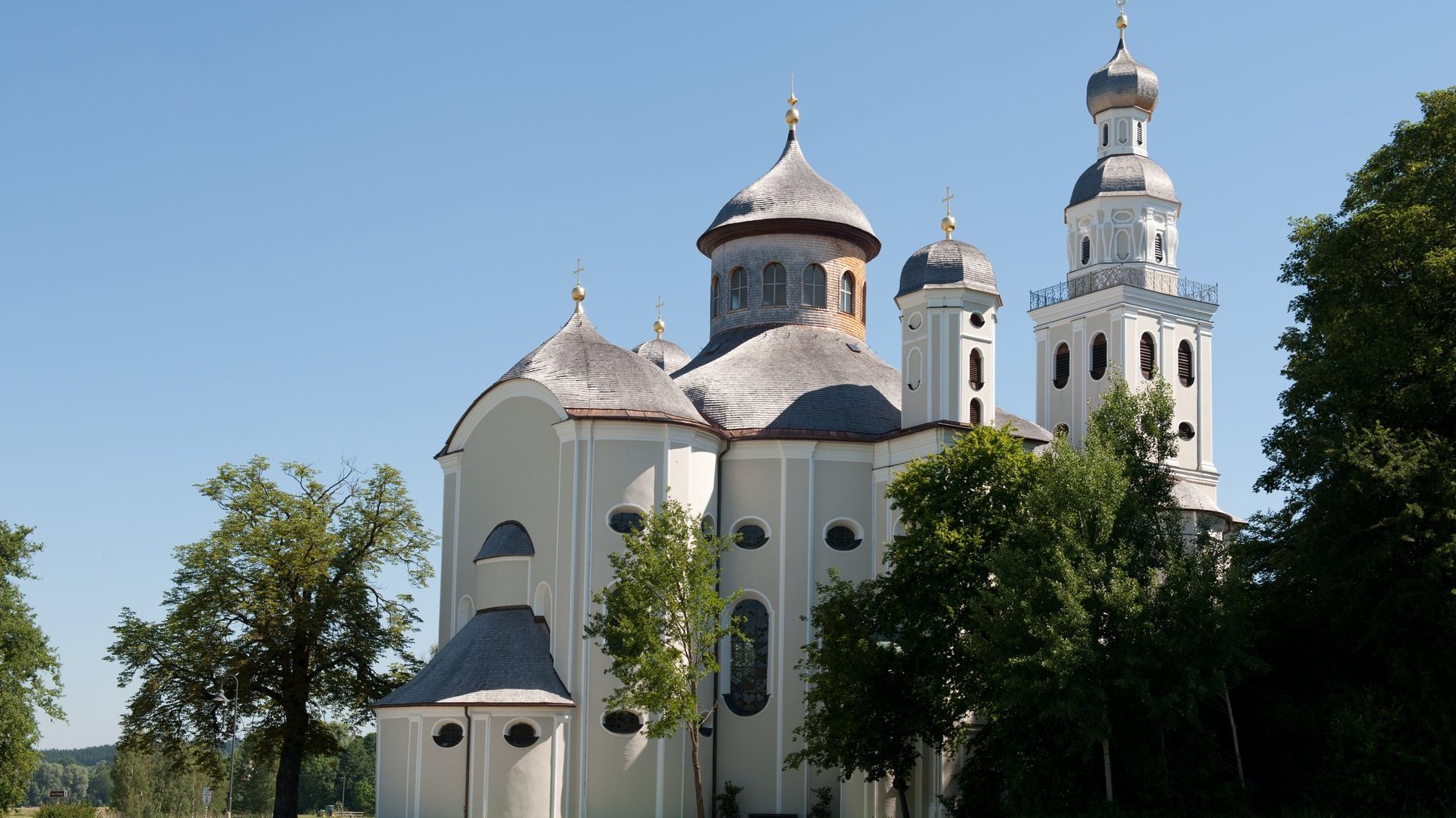 Kirchtürme bei schönem Wetter mit Wiese und Bäumen